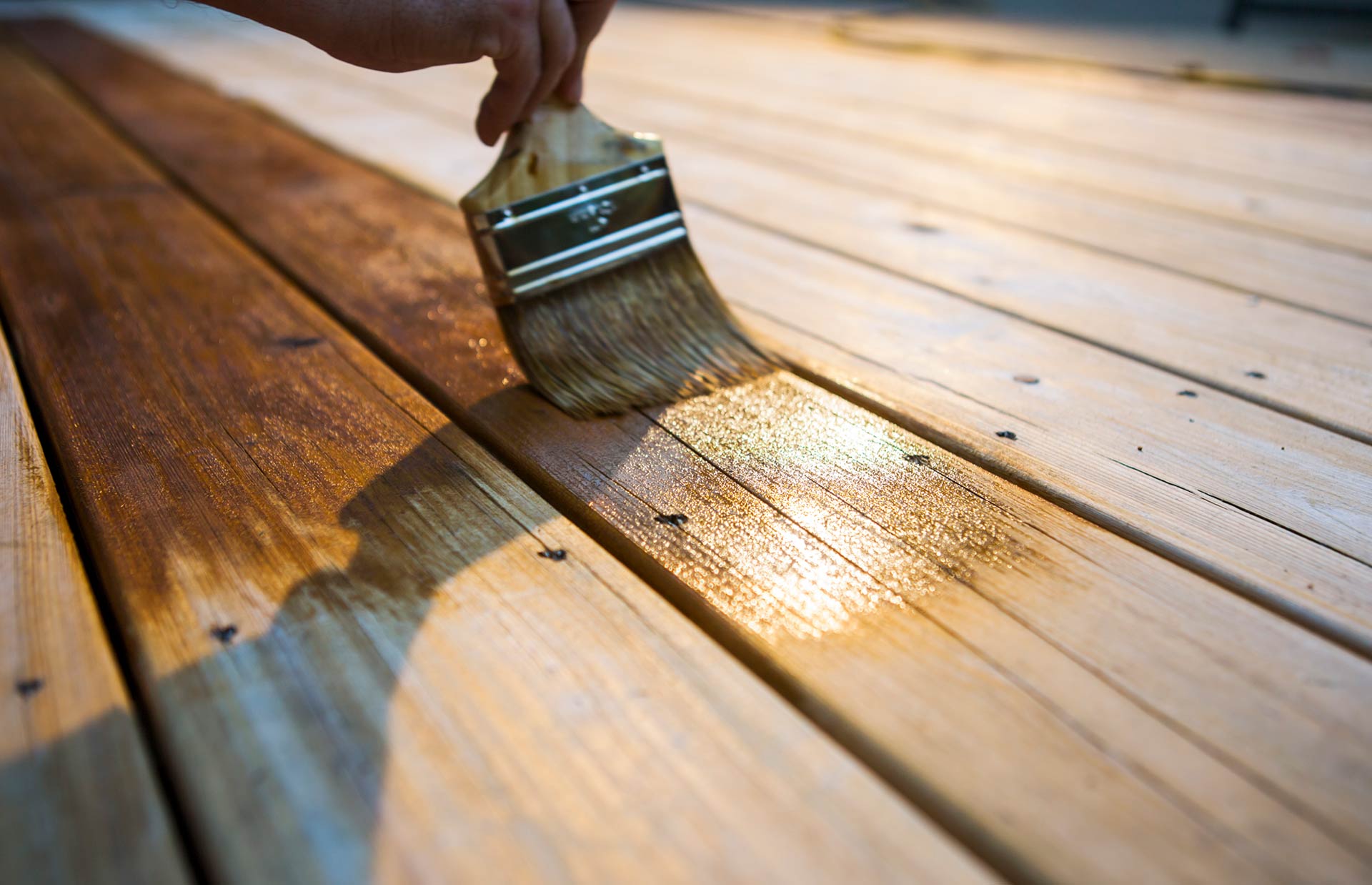 Nahaufnahme Pinsel mit dem eine Holzterrasse gestrichen wird