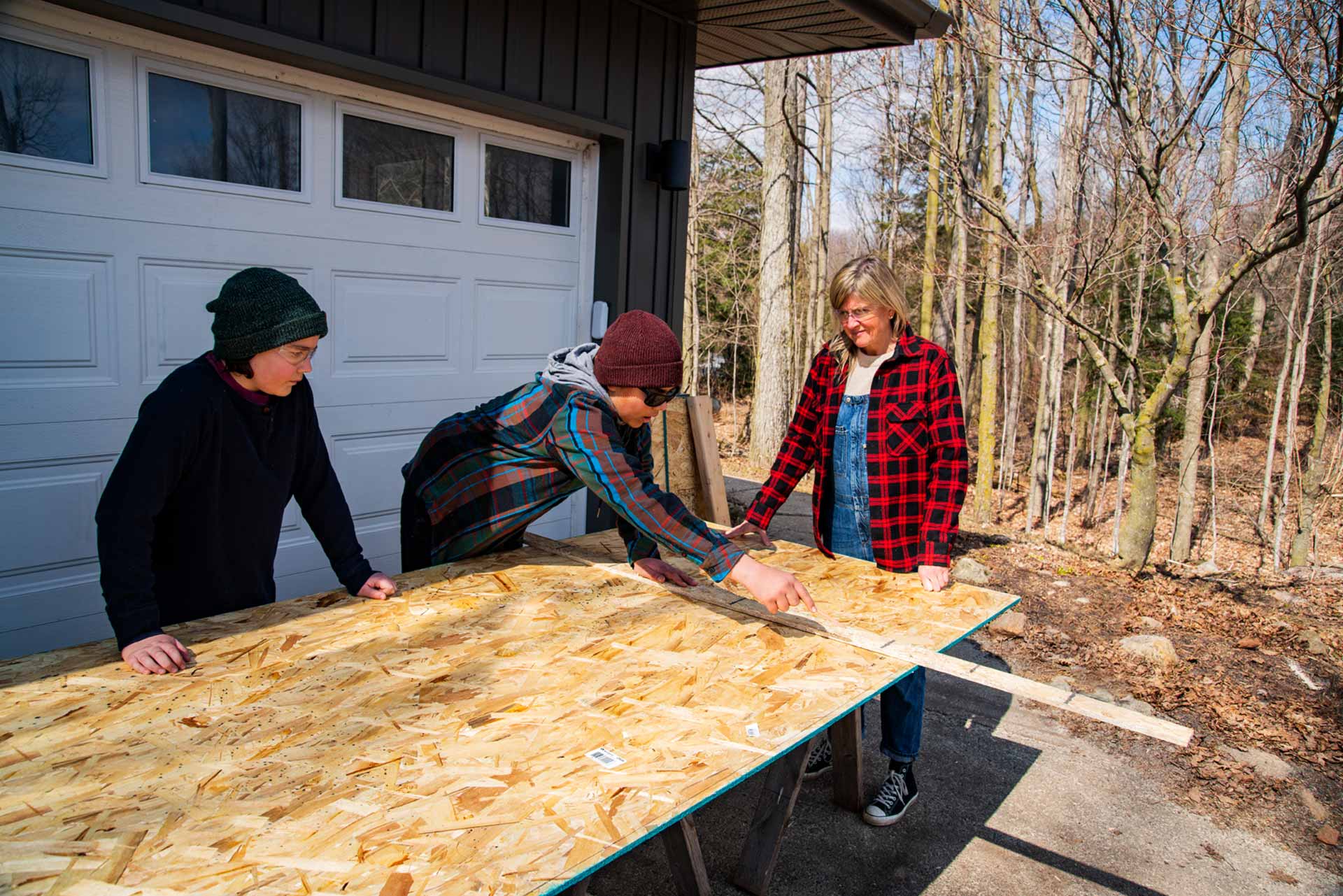 Familie vor Garage misst OSB-Platte