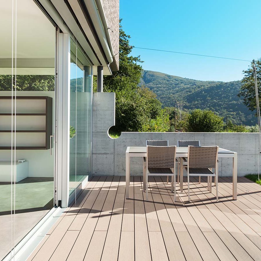 Holzterrassendielen vor verglastem Terrassenzugang mit Waldlandschaft im Hintergrund